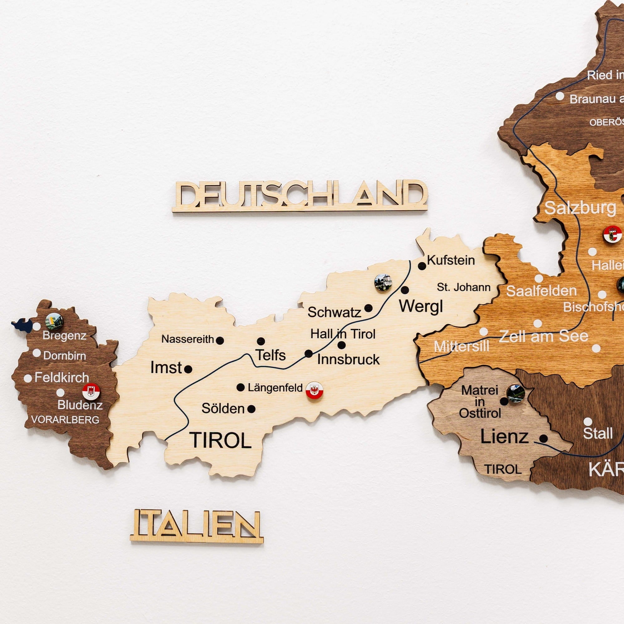 Wooden map of Austria and Germany with city names labeled on a white background