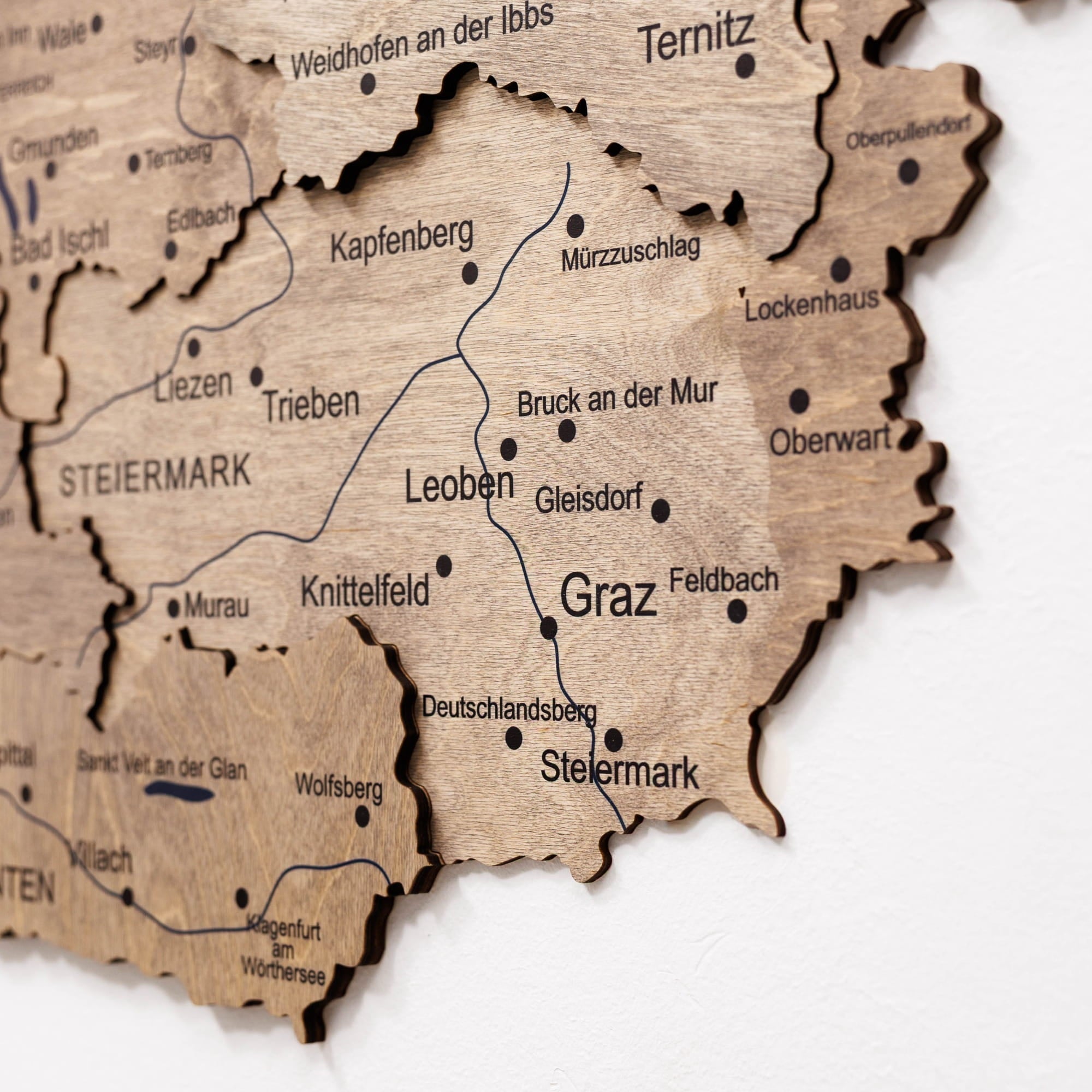 Wooden map of Steiermark with city names engraved on a white background