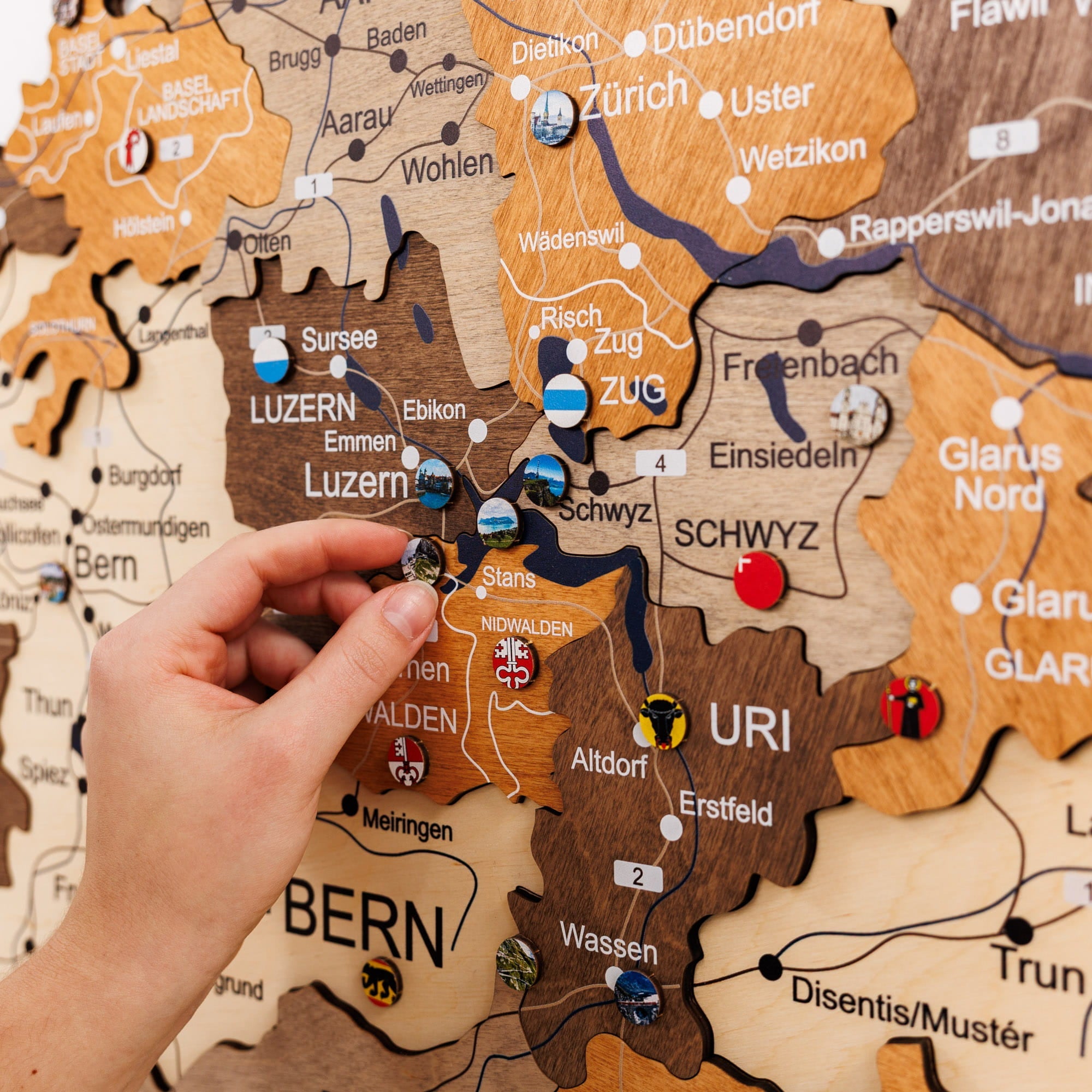 Hand interacting with a wooden map of Switzerland, highlighting regions.